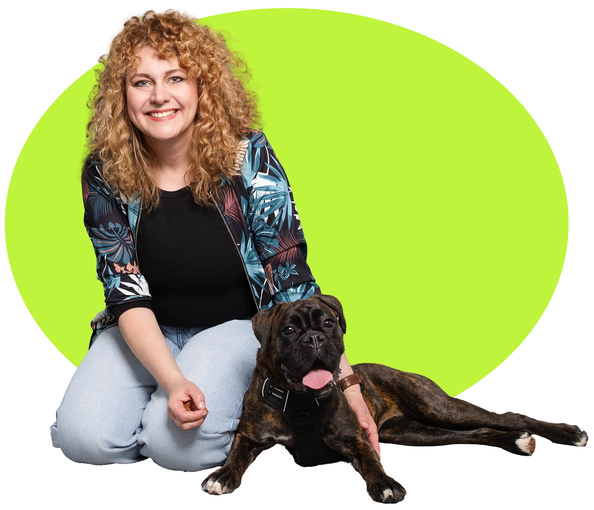 Hundetrainerin Kathrin von Deichpfoten kniet lächelnd neben ihrem brindlefarbenen Boxer vor grünem Hintergrund